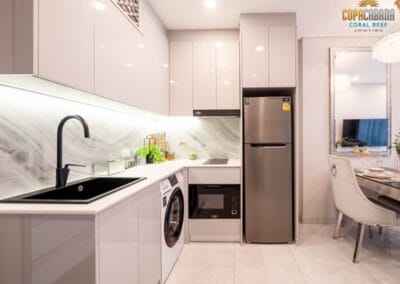 Modern white kitchen with built-in appliances and dining area in a tropical resort apartment.