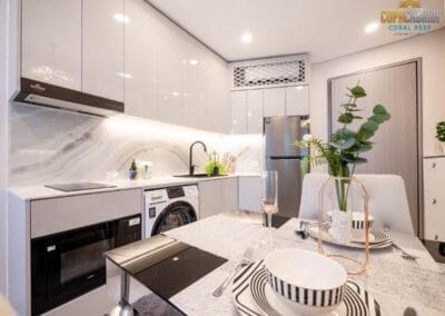 Modern white kitchen with dining area, flowers, and appliances in apartment SIAMIQ.