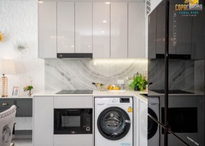 Súčasťou moderného bytu v apartmáne Siamiq, kuchynský priestor s bielymi skriňami a práčkou.