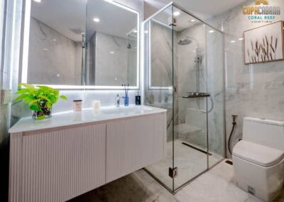 Modern hotel bathroom with glass shower enclosure, white fixtures, and decorative artwork.