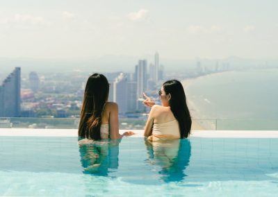 Relaxing women enjoying infinity pool with city view in Bangkok, Thailand.