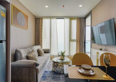 Modern living room with sofa, dining area, and balcony in a Thai-style apartment.