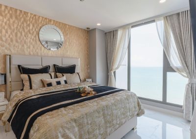 Luxusná spálňa s výhľadom na more, moderný interiér, pohodlná posteľ, slnečný deň.