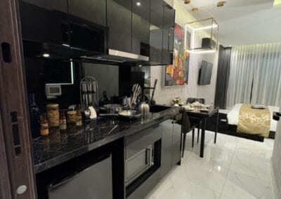 Modern hotel suite with kitchenette, dining area, and bedroom in Thailand.