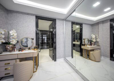 Elegant modern interior with mirrored wall, marble floor, and decorative flowers.