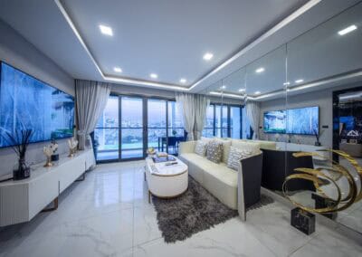 Modern living room with large windows, white sofa, and city view in Siamiq Thai apartments.